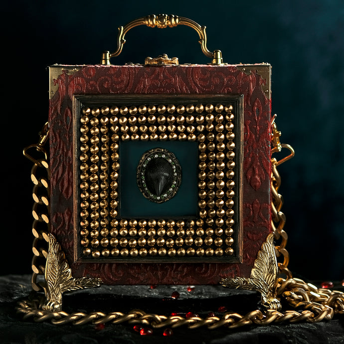 Framed raven head on red and cyan brocade hand bag
