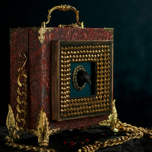 Framed raven head on red and cyan brocade hand bag