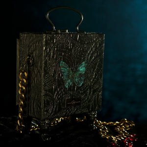 Cartera mariposa de Perséfone enmarcada sobre brocado bronce
