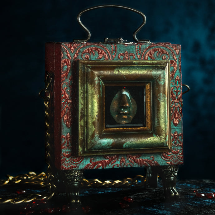 Framed resin nose on red and cyan brocade hand bag