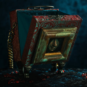 Framed resin nose on red and cyan brocade hand bag