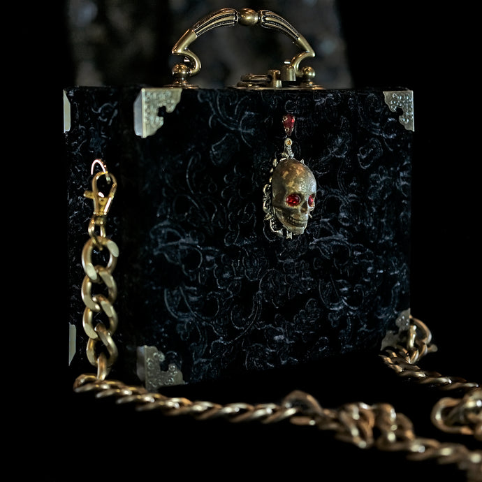 Cartera con calavera sobre terciopelo negro